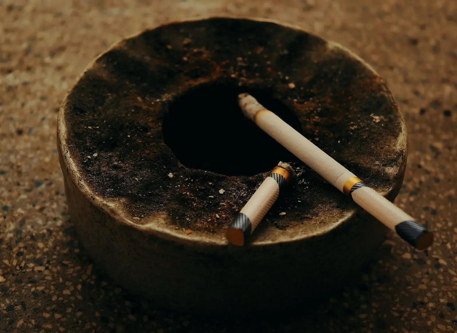 Cendrier ancien et deux cigarettes consumées, symbole de l'arrêt du tabac